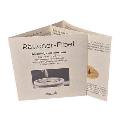 Das Titelbild der MAFUMO Räucher-Fibel zeigt das hochwertige, naturfarbene Cover im 10×10‑cm‑Format mit Räuchersieb‑Motiv. Es präsentiert die Anleitung zum Räuchern und gibt einen ersten Eindruck der Themen Räucherkohle, Räucherkegel, Räuchersieb, Palo Santo, Smudge und Räucherstäbchen.